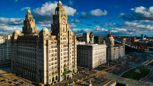 Dramatic skyline with historic buildings under a cloudy blue sky in Liverpool, UK.