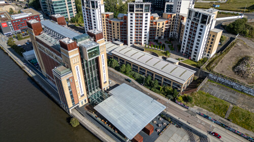 Aerial view of Baltic Flour Mills building, a contemporary art center, alongside modern apartments and a river  in Newcastle upon Tyne, UK.