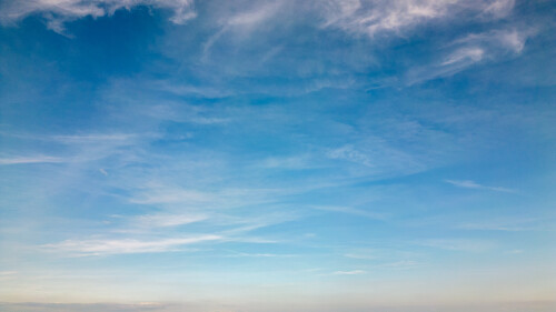 Serene blue sky with wispy white clouds, ideal for backgrounds or nature themes.