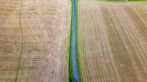 Aerial view of a rural landscape with a narrow road dividing agricultural fields.