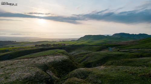 Serene landscape at sunrise with rolling hills and a gentle sky, showcasing the beauty of nature's tranquility.