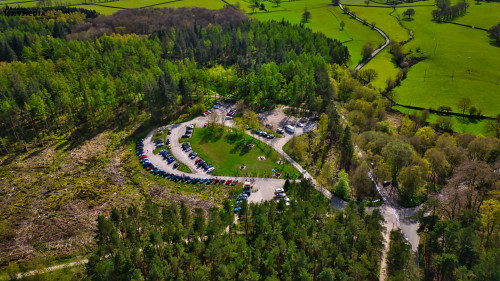 Aerial view of a parking lot surrounded by lush greenery and a winding river in a rural area.