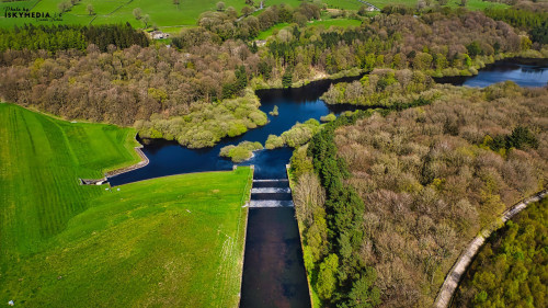 Aerial view of a lush green landscape featuring a river, lakes, and dense forests under a clear sky in Yorkshire