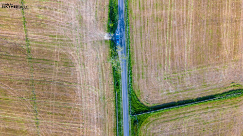 Aerial view of a green rural road dividing agricultural fields with patterns and textures.