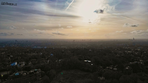 Aerial view of a cityscape at dusk with scattered clouds and a sunset glow.