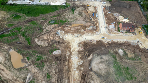 Aerial view of a construction site with dirt, machinery, and a partially built house at Bellway Homes in Boroughbridge, UK.