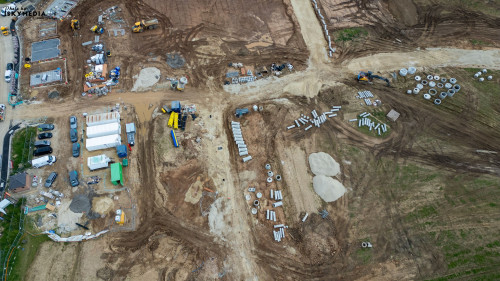 An aerial view of a construction site with various materials, vehicles, and equipment at Bellway Homes in Boroughbridge, UK.