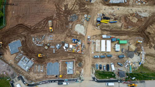 An aerial view of a construction site with various vehicles, materials, and partially built structures at Bellway Homes in Boroughbridge, UK.