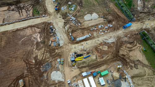 Aerial view of a construction site with various materials, machinery, and vehicles at Bellway Homes in Boroughbridge, UK.