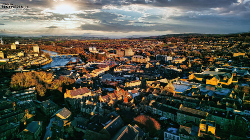Aerial view of a city Lancaster at sunset with warm lighting, highlighting the urban landscape and river.
