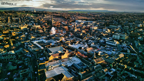 Aerial view of a city Lancaster at sunset with warm lighting highlighting the buildings and streets, showcasing the urban landscape.